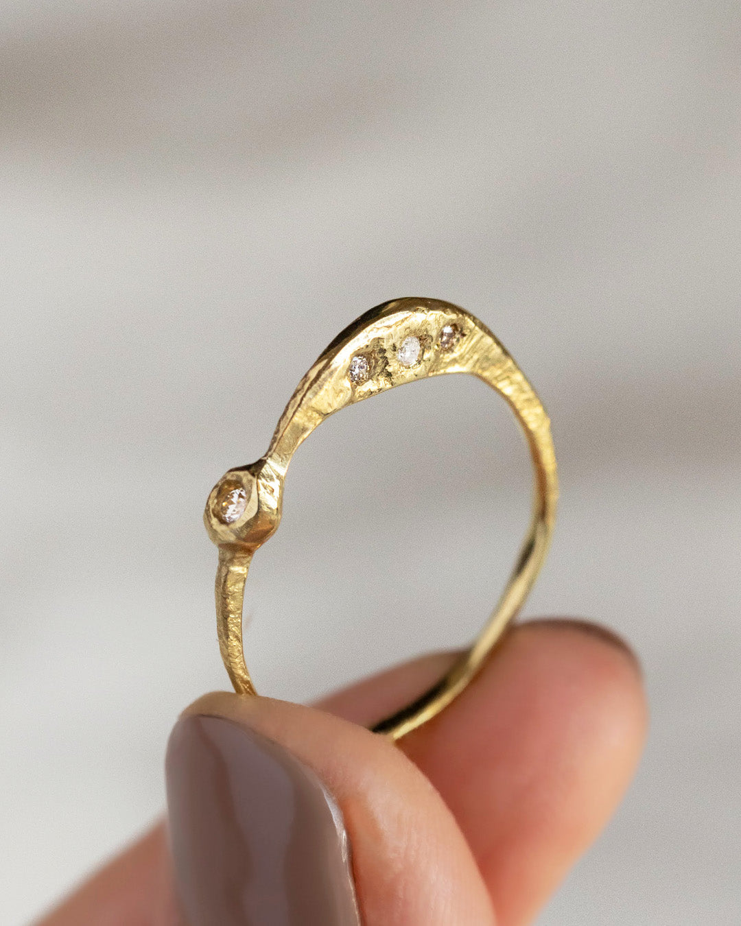 三日月のイメージで形作られたリングを指で掲げている