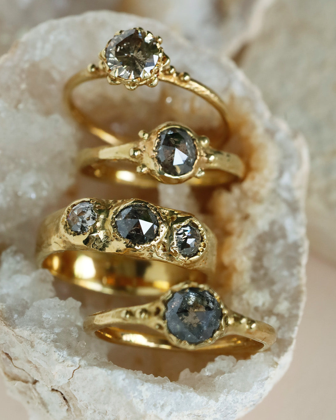 原石の中にソルトアンドペッパーダイヤモンドの大ぶりのリング4本が並べられている