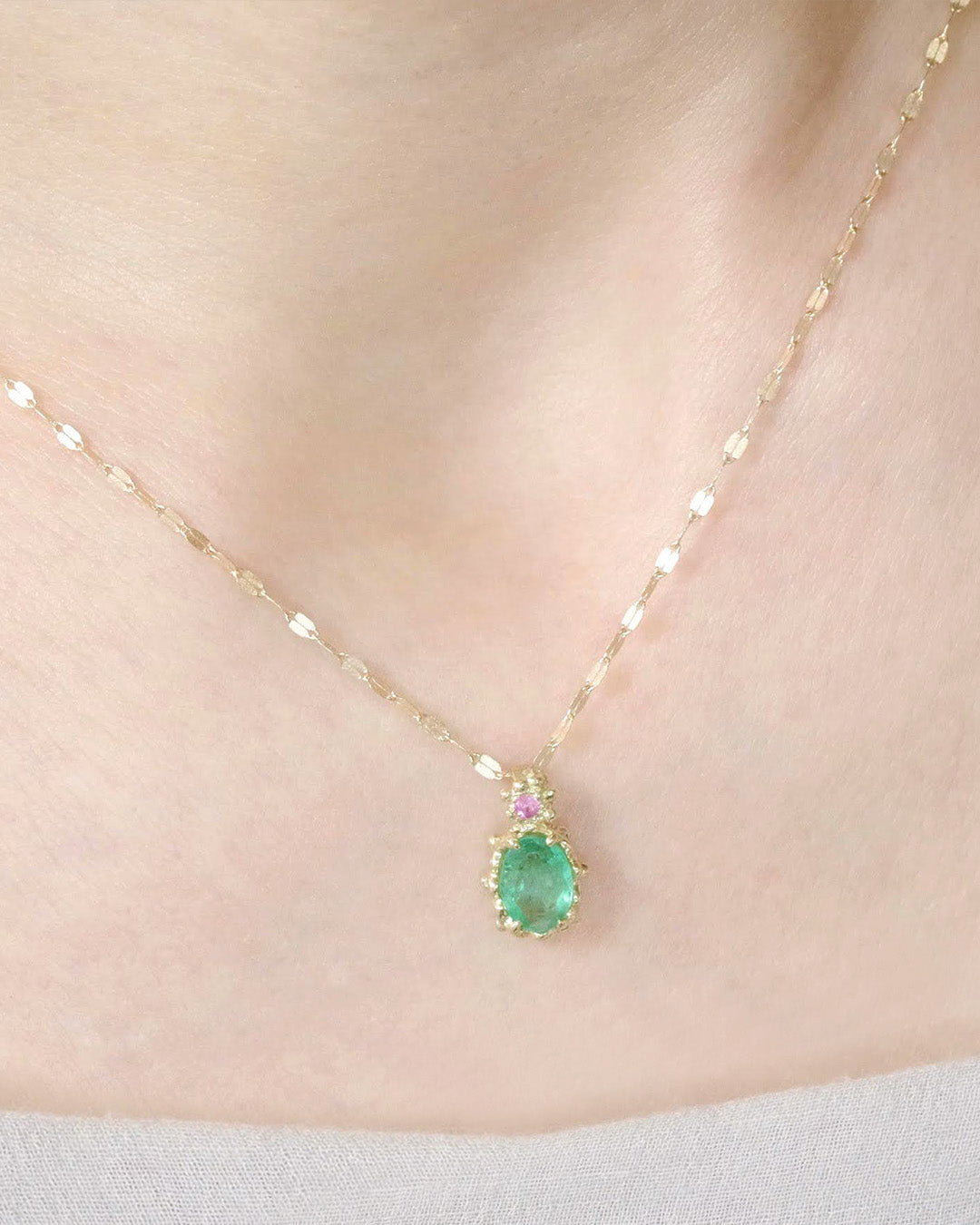 白いデコルテに着用したエメラルドのネックレス